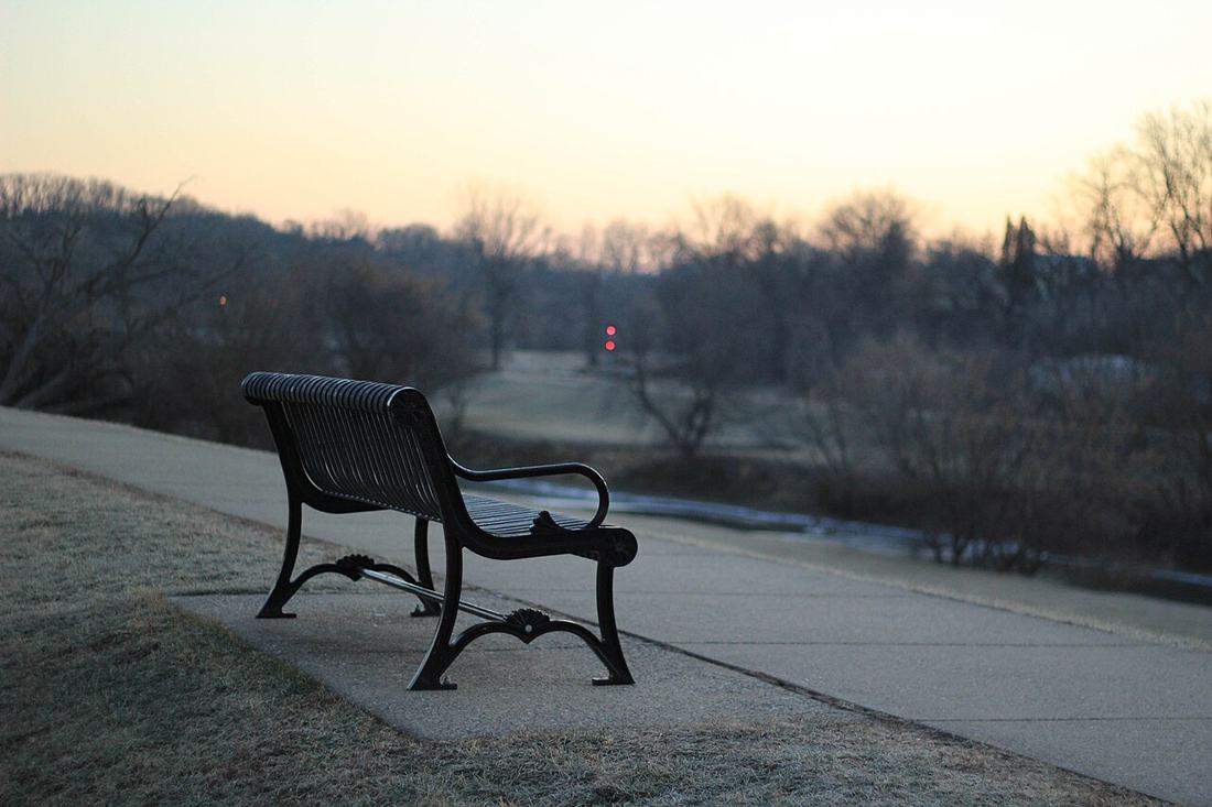 An empty park bench at dusk